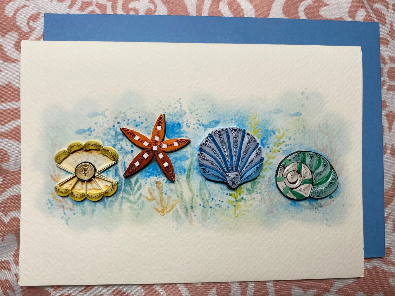 Set of four colorful quilled seashells on a card with a decorative background